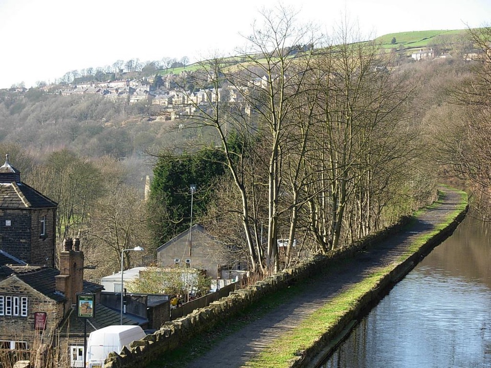 Stone houses stepping up the wooded valley side above the canal at Hebden Bridge