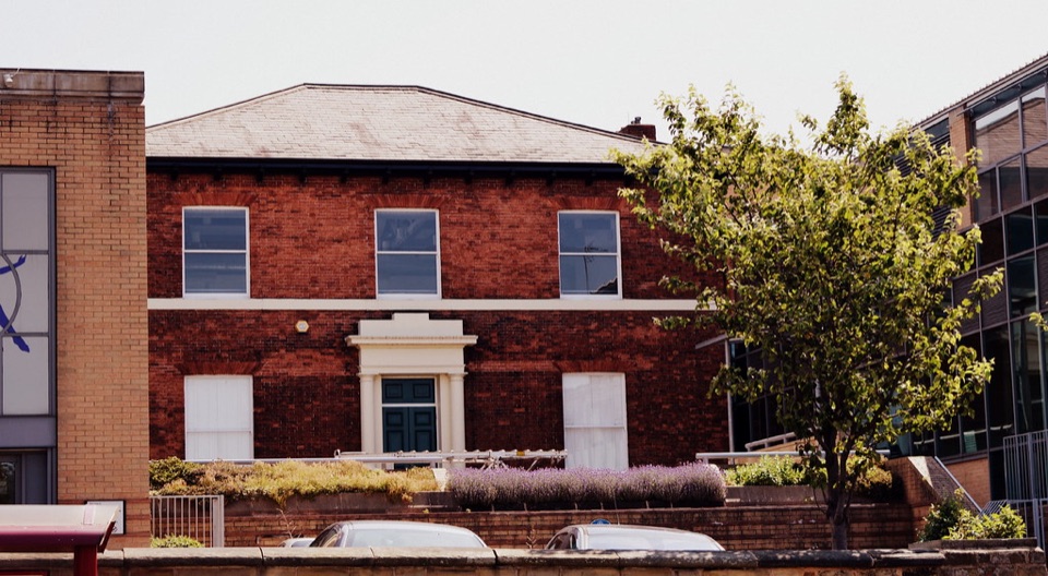 A brick building with a slate roof behind a garden wall at Chapeltown in Leeds