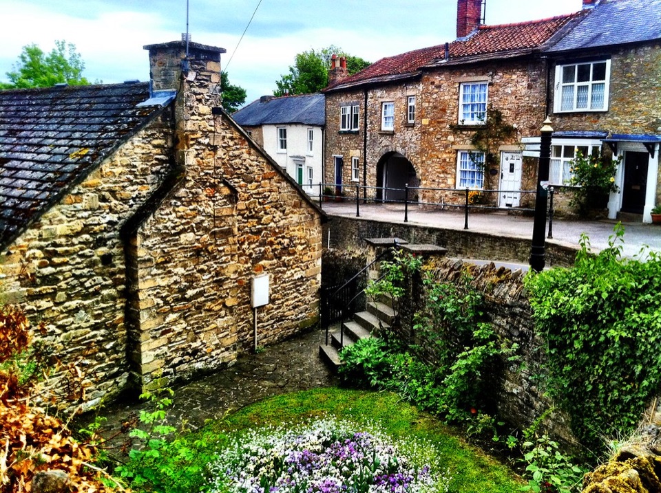 A blank stone gable end beside stone houses on a village street at Richmond in North Yorkshire