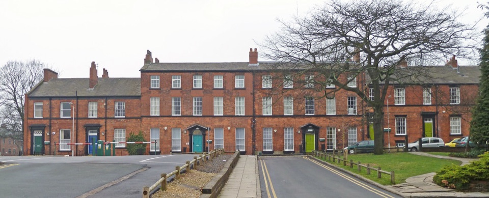 A long red brick terrace on Lyddon Terrace in Leeds seen from the road